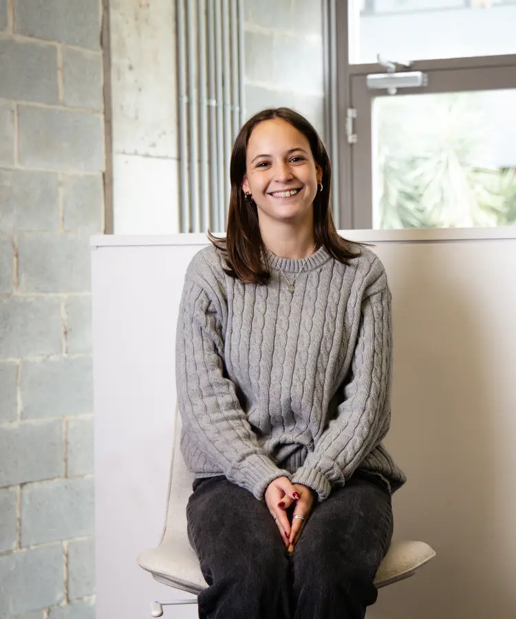 Bella, the receptionist, sits comfortably on a chair with a welcoming smile.