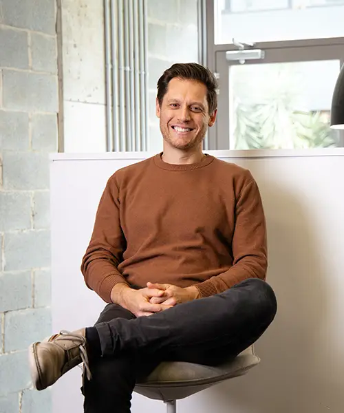 Cameron Hobbs, physiotherapist, sits comfortably on a chair with a welcoming smile