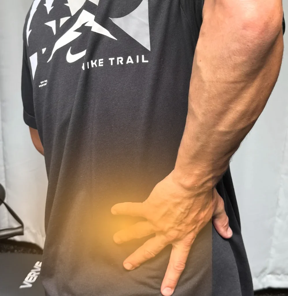 Person from behind touching their lower back, highlighted with an orange glow to indicate Lower Back Pain