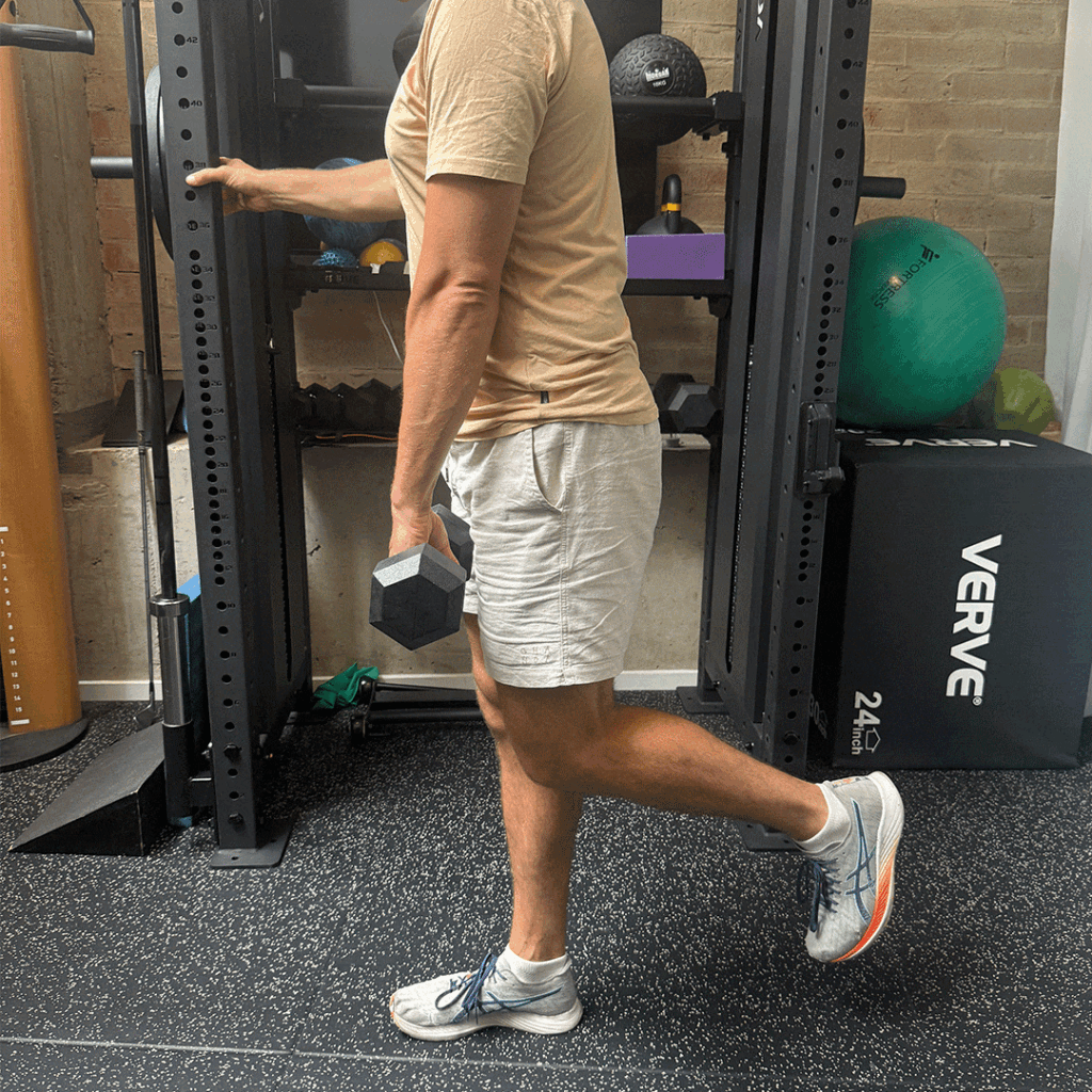 Person in a gym-home performing a single-leg Romanian deadlift, holding a dumbbell in one hand for the exercise